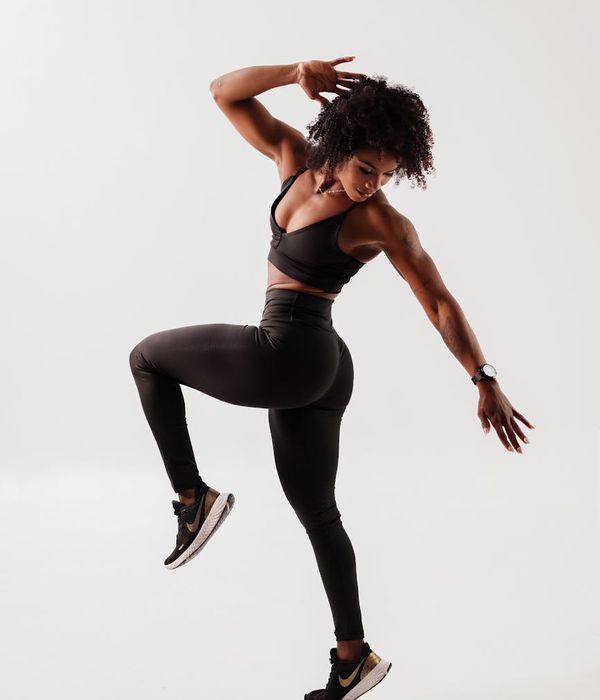 Woman performing a dynamic cardio movement in a modern studio.
